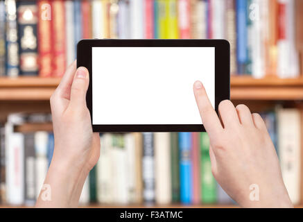 finger touches tablet pc screen with cut out screen on front of bookcase Stock Photo