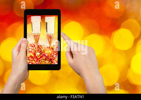man takes photo of Christmas still life - two glasses of champagne with blurred background from big red and yellow twinkling Xma Stock Photo