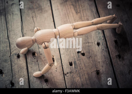 Wooden figurine practicing crank on an old wooden table.
