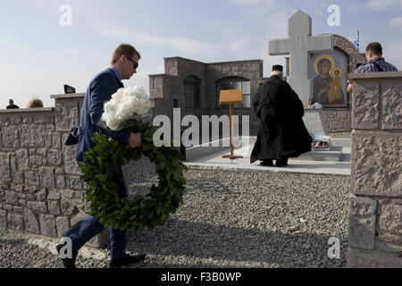 Lemnos island, Greece. 3rd October, 2015. Mr. Vladimir Potapov, Consular attache of the Russian Federation in Thessalonica, carries a wreath to be laid on the memorial during the ceremony event. Punta cape, Russian-Cossack memorial/ graveyard. Punta cape, Lemnos island, Greece. Credit:  BasilT/Alamy Live News Stock Photo