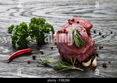Raw beef steak with spices on a dark wooden background Stock Photo