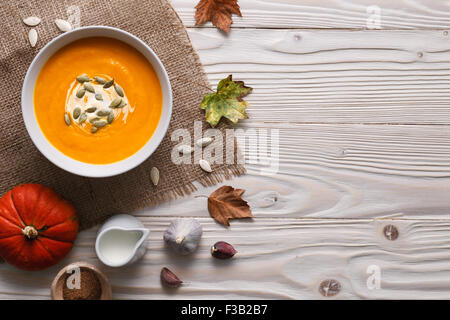 Traditional pumpkin soup with seeds and ingredients still life. Stock Photo