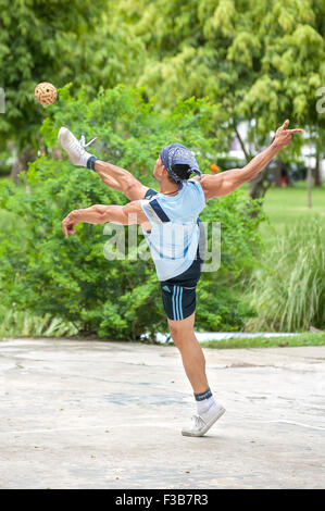 Thai man playing the popular Asian sport of Sepak takraw in Lumpini Park, Bangkok Stock Photo