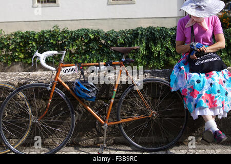 Tuscany, Italy. 3rd Oct, 2015. A bike fancier rests with her old bike outside the ' Eroica (heroic)' vintage bike market in Gaiole in Chianti of Tuscany, Italy, on Oct. 3, 2015. A vintage bike market was held in Gaiole in Chianti from October 2 to October 4, as a part of the 'Eroica (heroic)' cycling race for old bikes, which was founded in 1997, and takes place every October in Gaiole in Chianti. More than 5,500 participants from all over the world were attracted in this non professional event for classic bikes this year. © Jin Yu/Xinhua/Alamy Live News Stock Photo