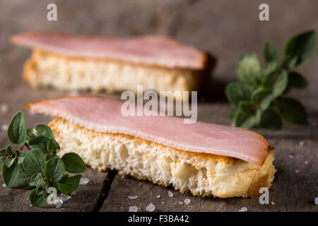 Toasted bread slices with smoked meat over rustic wooden background Stock Photo