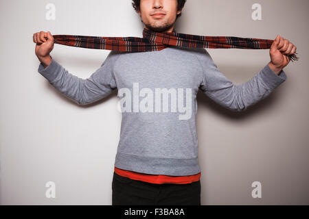 A young man with a scarf around his neck is standing against a split colored green and white background Stock Photo