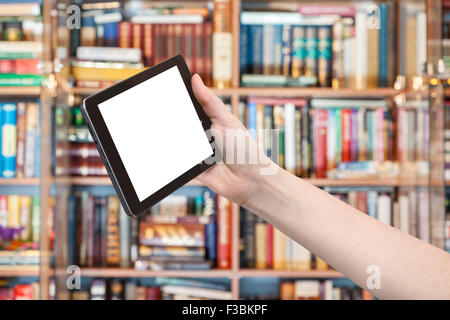 hand holds tablet pc with cut out screen and library on background Stock Photo