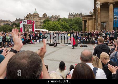 Crowds enjoying Edinburgh Fringe Festival 2015 act 'Funny Bones Trash' outside the Scottish National Gallery