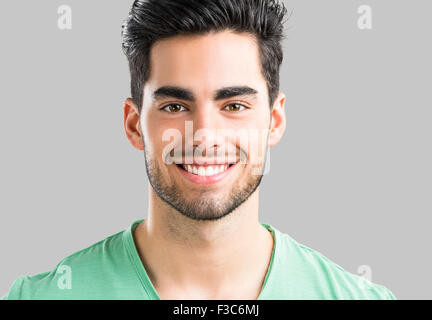 Portrait of handsome young man smiling, isolated on gray background Stock Photo