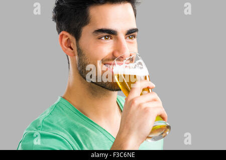 Portrait of handsome young man tasting a draft beer, isolated on gray background Stock Photo