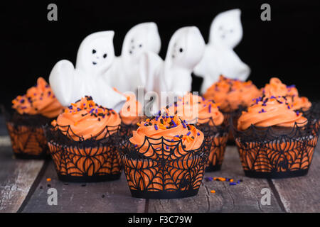 Festive Halloween cupcakes on rustic background with ghosts Stock Photo
