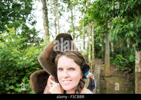 Woolly monkey on the head of a tourist woman in the Amazon near Iquitos, Peru Stock Photo