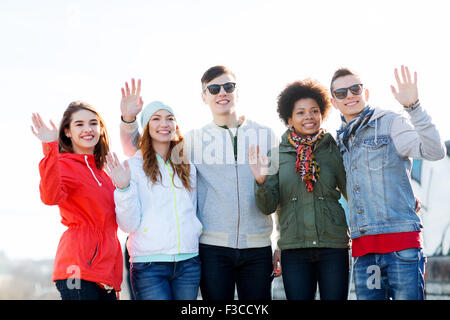 happy teenage friends waving hands on city street Stock Photo