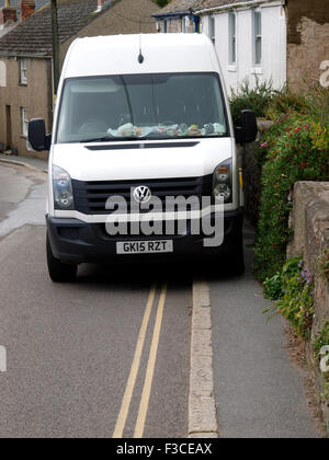 Vehicle parked on pavement blocking the pavement so pedestrians have to walk on the road, Cornwall, UK Stock Photo