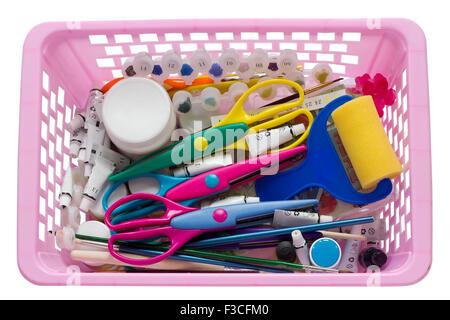Scrapbooking tools in pink plastic basket - scissors, paper, brushes, tubes with paints and so on. Isolated Stock Photo