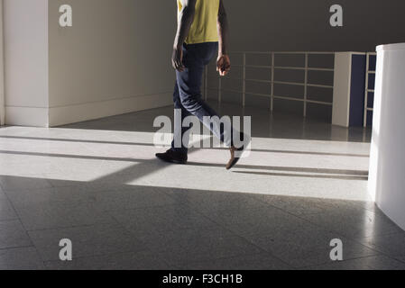 Man walking along building hallway, low section Stock Photo