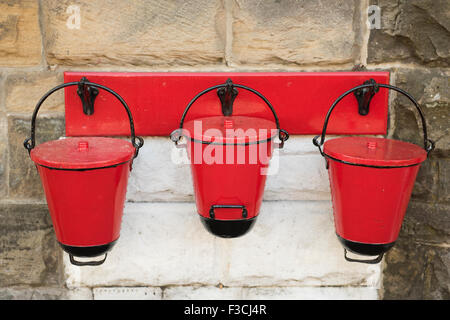 Three Red fire buckets, these are hanging at Goathland station on the North Yorkshire Moors Railway. Stock Photo