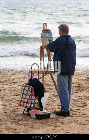 Artist captures the beauty of the Bournemouth seaside and coastline at Bournemouth beach, Dorset UK in October - painting on easel Stock Photo