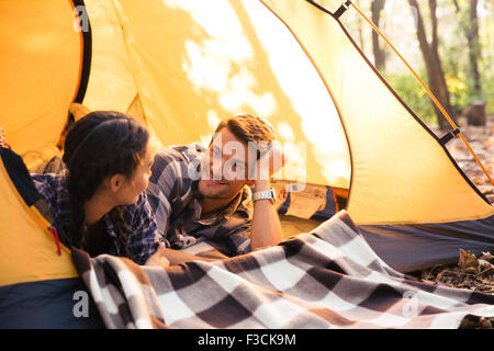 Portrait of a happy couple lying in a tent in the forest Stock Photo