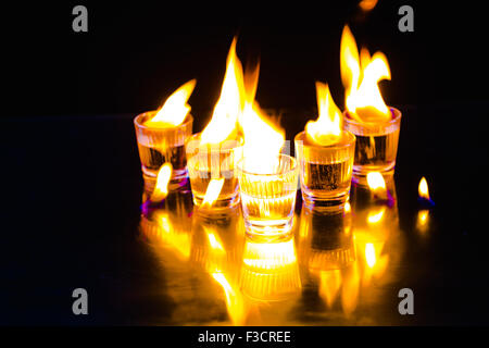 Glass with whiskey splash  and fire on black background Stock Photo