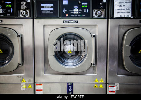 A row of industrial washing machines in a public laundromat Stock Photo