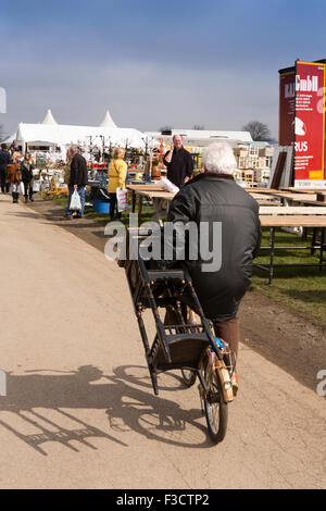 UK, England, Lincolnshire, Lincoln, Antiques Fair, man riding bicycle, whilst carrying small table Stock Photo