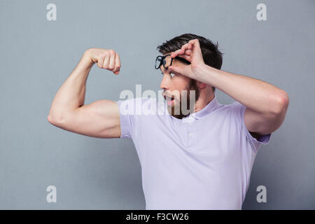 Potrait of a man looking at his biceps with delight over gray background Stock Photo