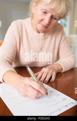 Senior Woman Signing Last Will And Testament At Home Stock Photo