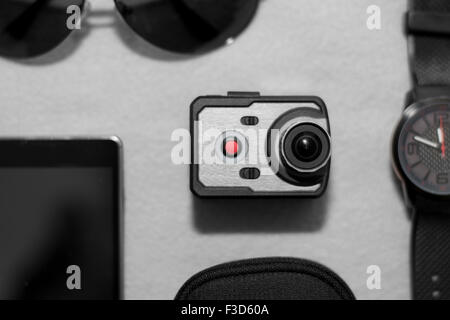 Wristwatch, sunglasses, smart phone and very small action camera layed down on floor. Male accessories. Stock Photo