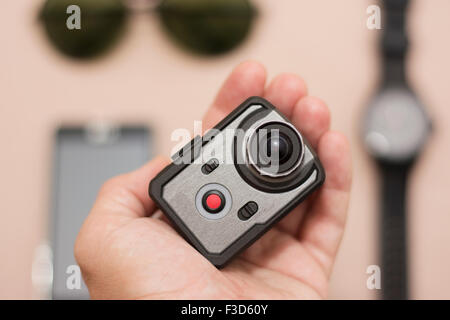 Wristwatch, sunglasses, smart phone and very small action cameraas part of new male accessories. Action camera in hand showing t Stock Photo
