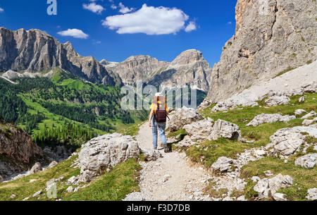 hiker on footpath  in Sella mountain, on background Colfosco and Badia Valley, south Tyrol, Italy Stock Photo