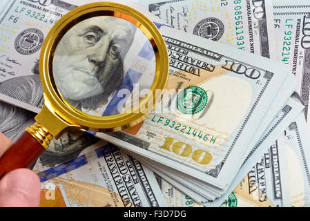 Hundred dollar banknotes under magnifying glass Stock Photo