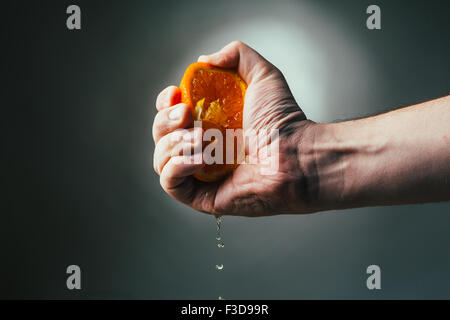 man dramatic squeezes orange. Concept squeezed a man  is tired from work. Stock Photo