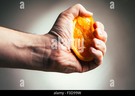 man dramatic squeezes orange. Concept squeezed a man  is tired from work. Stock Photo