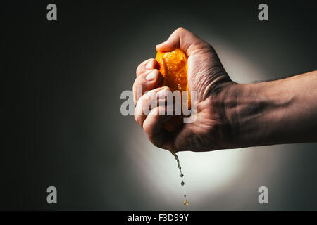 man dramatic squeezes orange. Concept squeezed a man  is tired from work. Stock Photo