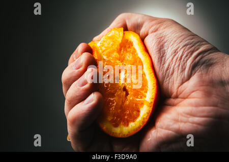 man dramatic squeezes orange. Concept squeezed a man  is tired from work. Stock Photo