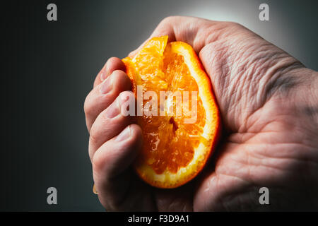 man dramatic squeezes orange. Concept squeezed a man  is tired from work. Stock Photo