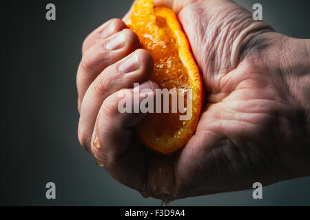 man dramatic squeezes orange. Concept squeezed a man  is tired from work. Stock Photo