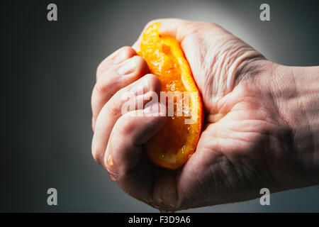 man dramatic squeezes orange. Concept squeezed a man  is tired from work. Stock Photo