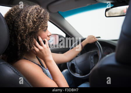 Young woman using phone while driving car Stock Photo