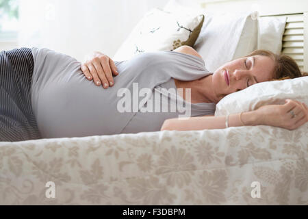 Pregnant woman sleeping in bed Stock Photo