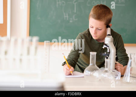 Boy (8-9) taking notes in classroom Stock Photo