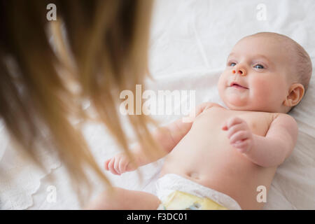Mother playing with baby girl (2-5 months) on bed Stock Photo