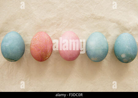 Dyed Easter eggs in a row on beige Stock Photo