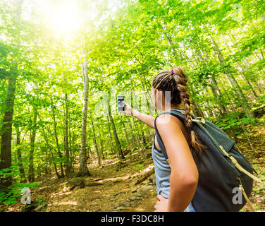 Female hiker looking at compass on phone Stock Photo