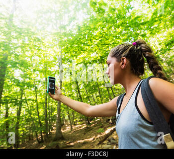Female hiker looking at compass on phone Stock Photo