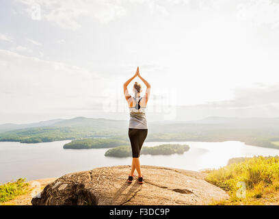 Rear view of young woman practicing yoga in front of lake Stock Photo