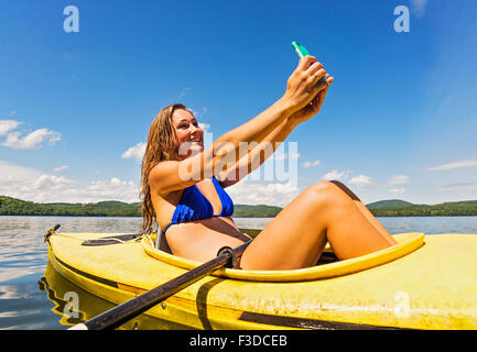 Young woman taking selfie in kayak on lake Stock Photo