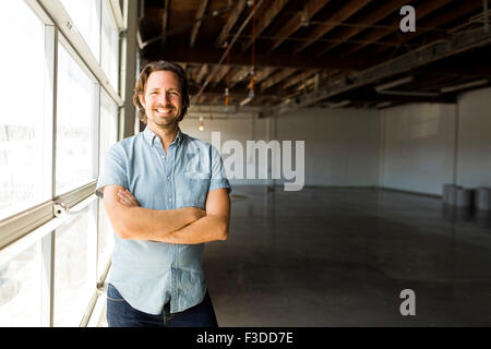 Man standing by window in warehouse Stock Photo