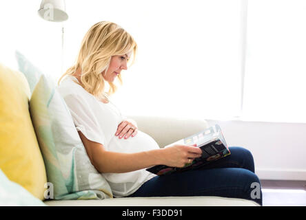 Pregnant woman reading book at home Stock Photo